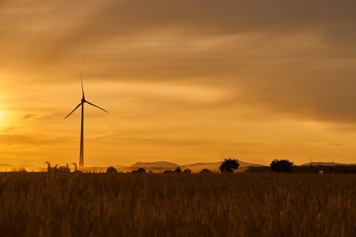 a single windmill in a field at dusk